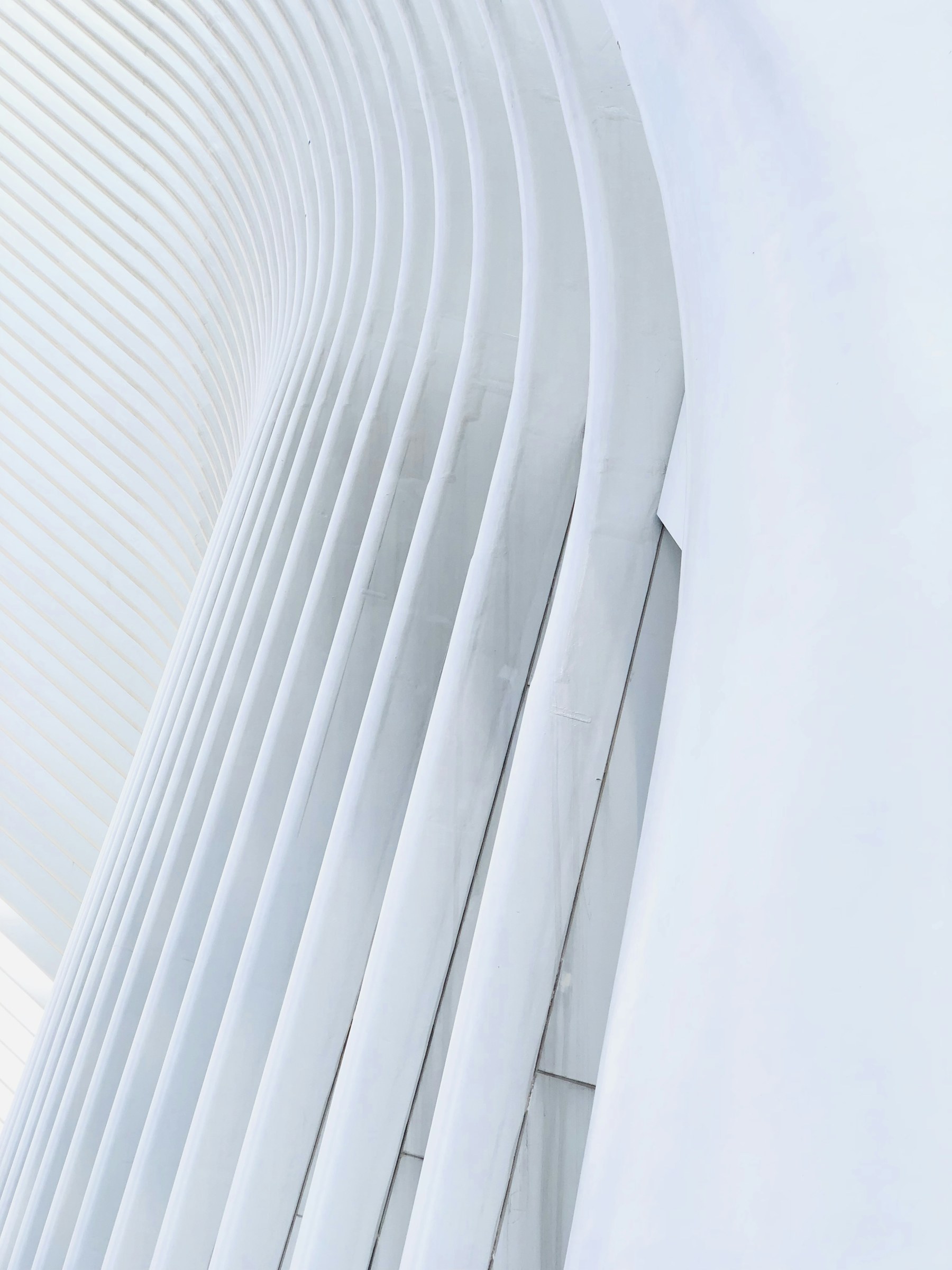 Minimal white architectural ribs dissolving into pale blue light