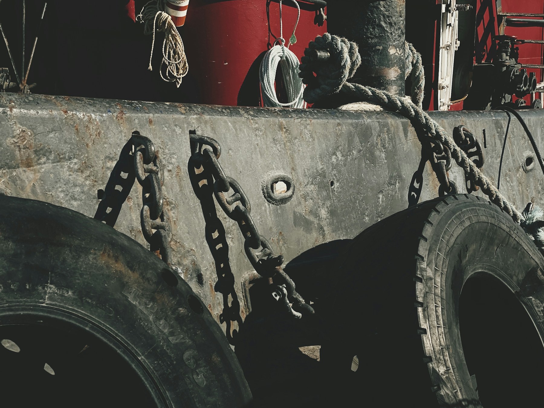 Industrial tires, chains and a red cabin arranged in a dark mechanical composition