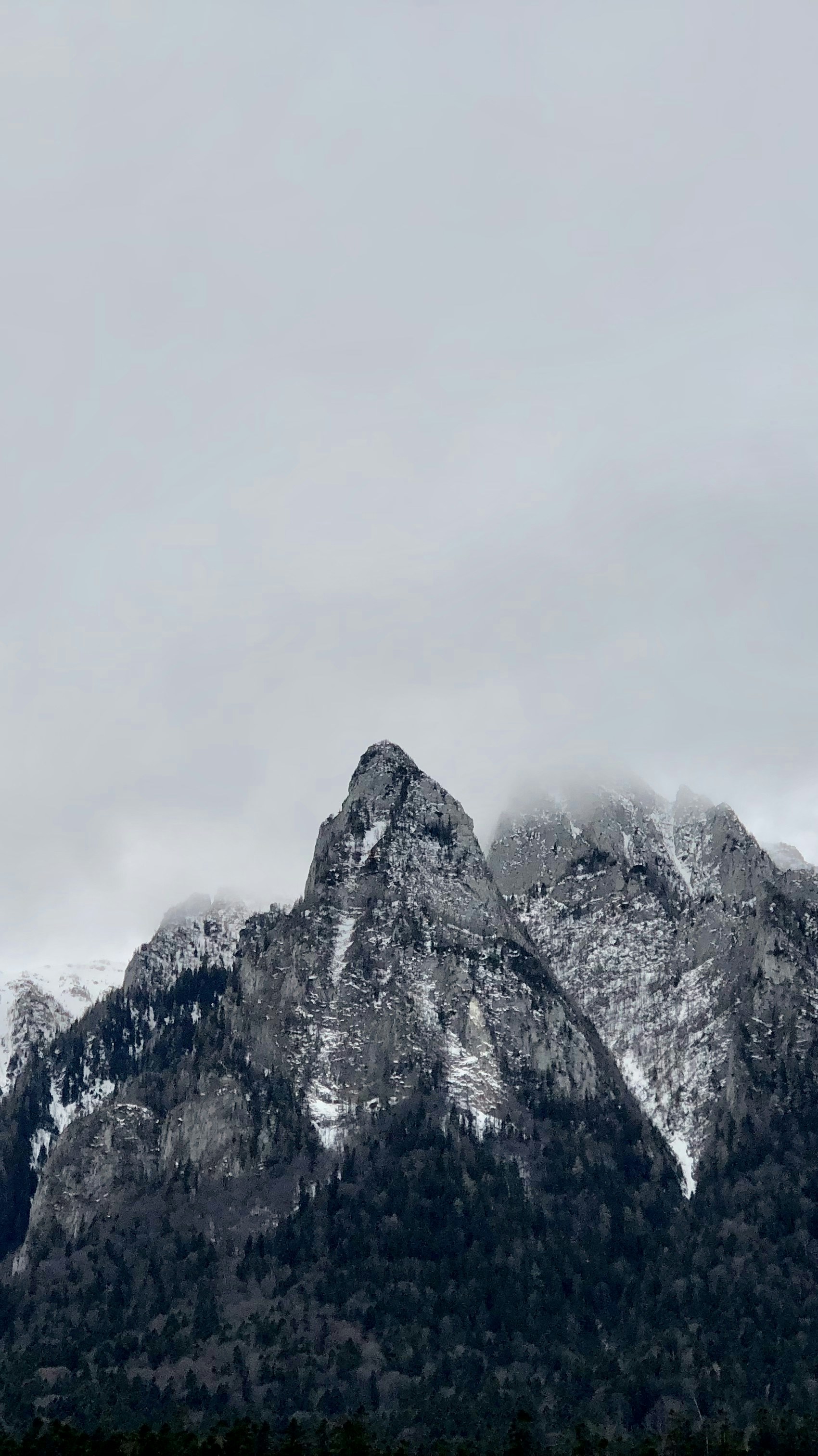 A sharp black mountain emerging from cloud and winter mist in Romania